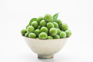 Many Green plum fruits on a traditional korean bowl