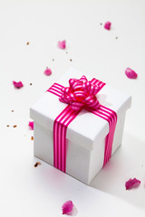 White gift box with pink ribbon and plum petal 