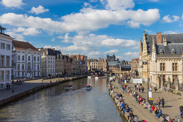 GHENT, Belgium - APRIL 10, 2016: A lot of people sitting on the waterfront of river Leie along Graslei street in Ghent