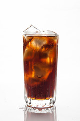 Cola with ice in a glass on white background