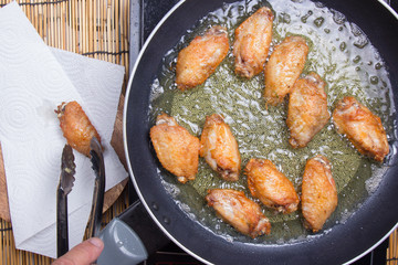 Chef frying chicken wings in pan