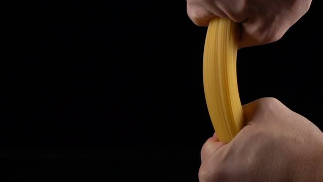 hands breaking a bunch of spaghetti