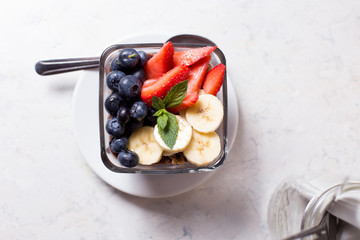 Accii bowl with strawberries, blueberries, banana, granola, and honey.