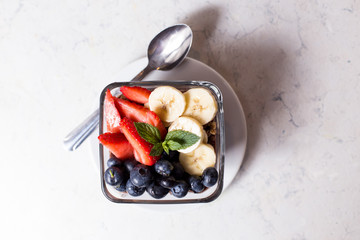 Accii bowl with strawberries, blueberries, banana, granola, and honey.