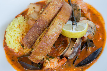 Seafood Stew: shrimp, mussels, clams, calamari, fish, tomato-saffron broth, saffron rice