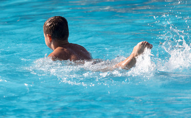 Obraz na płótnie Canvas boy swims with a splash in the water park