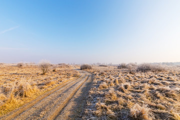 Bright winter scenery, with frozen vegetation and frost covered country road, on a cold and crisp, sunny, day