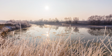 Winter scenery, with frozen river and frost cover vegetation on a cold, sunny, day