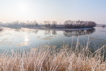 Winter scenery, with frozen river and frost cover vegetation on a cold, sunny, day