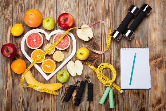 Diet, centimeter and dumbbells on a wooden background