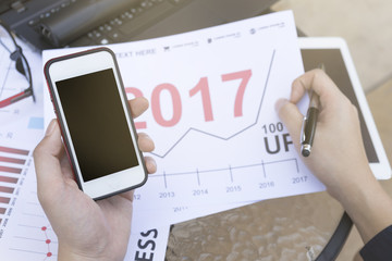 Business man using  smartphone and tablet for analytic financial graph year 2017 trend  forecasting planning outdoor place