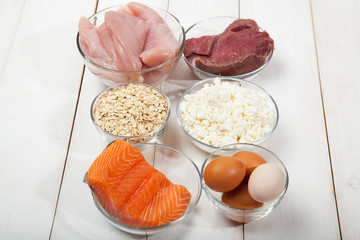 Proteins, fish, cheese, eggs, meat and chicken on a white wooden background