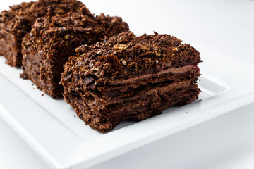 French Chocolate Napoleon cake of puff pastry with sour cream on a white plate close-up. Nutritious dessert. Selected Focus