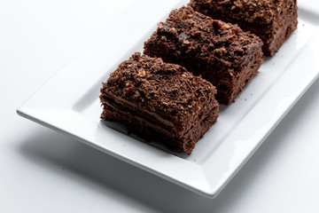 French Chocolate Napoleon cake of puff pastry with sour cream on a white plate close-up. Nutritious dessert. Selected Focus