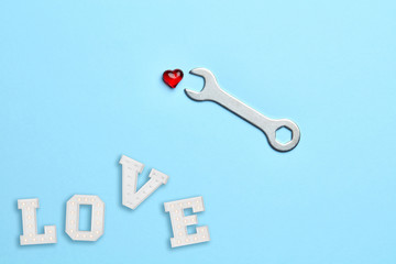 Blue empty background with wrench fixing little red heart and love 