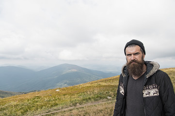 man hipster traveler with beard and moustache portrait on mountain