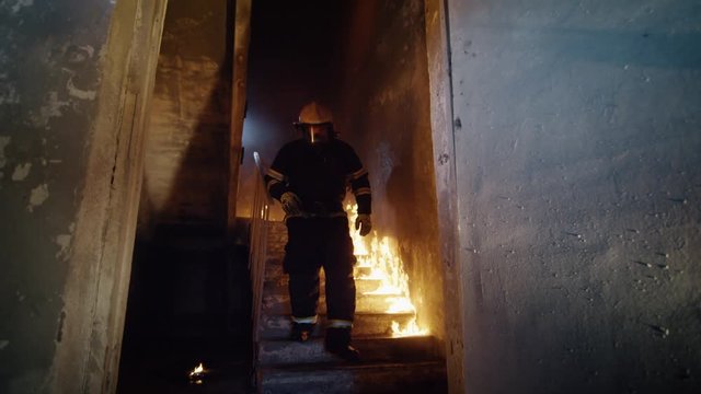 Fully Equipped Firefighter Runs Down on Burning Stairs. Building on Fire. Slow Motion. Shot on RED EPIC (uhd).
