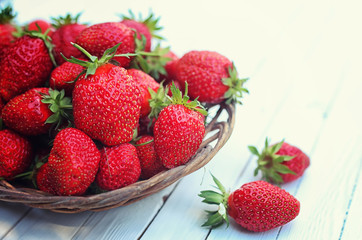 Strawberry in wicker plate on wooden background
