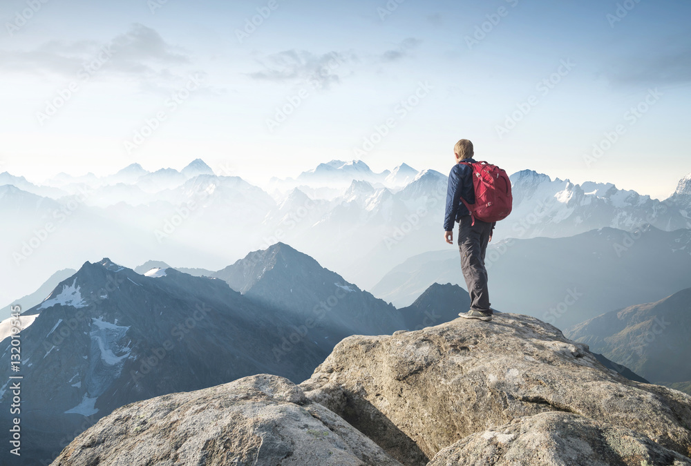 Wall mural Tourist on the peak of high rocks. Sport and active life concept..