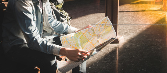 Traveler sitting and looking in map for waiting train at train station. Travel concept by train...