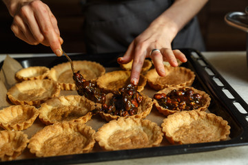 Young woman making delicious cakes with nuts.
