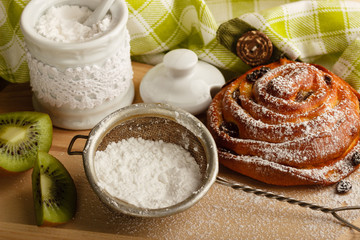 Bun with raisins and sugar powder in the strainer