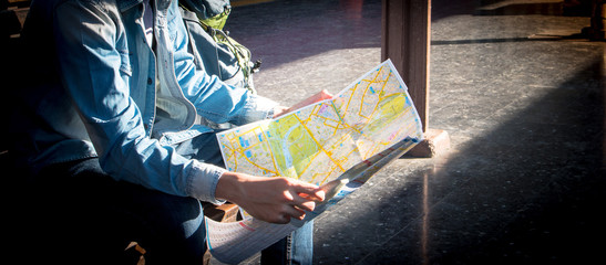 Traveler sitting and looking in map for waiting train at train station. Travel concept by train with vintage tone.