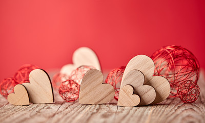 Different size heart figures on wooden table and red background with bauble