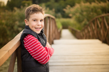 Smiling boy on a wooden bridge looking at the camera