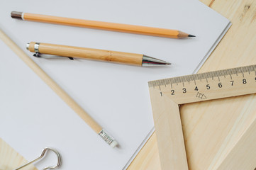 Wood pencil, pen, triangle, briefpapier clip on the desk in daylight. Office table