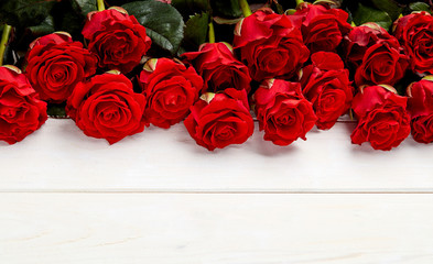 Buds of red roses on white wooden background