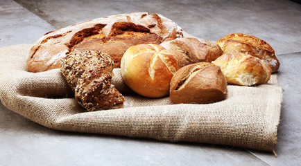 Different kinds of bread rolls on black board from above. Kitchen or bakery poster design.