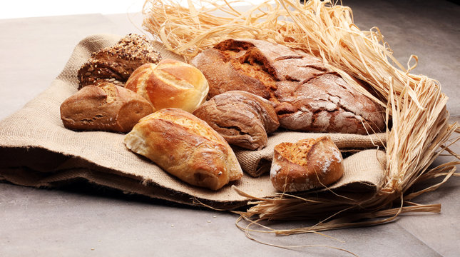 Different kinds of bread rolls on black board from above. Kitchen or bakery poster design.