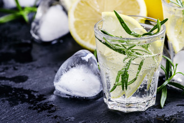 Refreshing lemon drink with rosemary, ice and tonic, black stone
