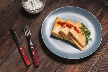Pancakes with red caviar on plate. Russian cuisine.