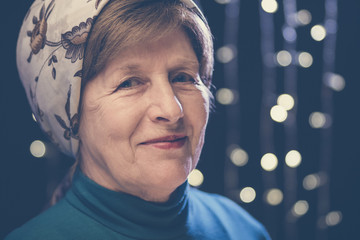portrait of a wrinkled face kind grandmother in a headscarf with bokeh