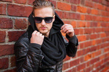 Fototapeta premium Stylish man in the city standing by the brick wall