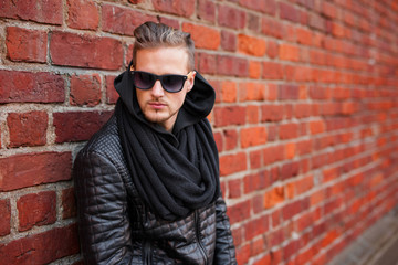 Handsome man with sunglasses standing by the brick wall