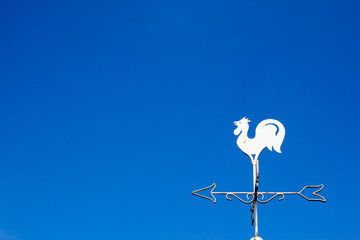 White rooster weather vane show the wind direction on blue sky b