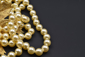 Pearls and glittering golden leaf with black background. Copy space.