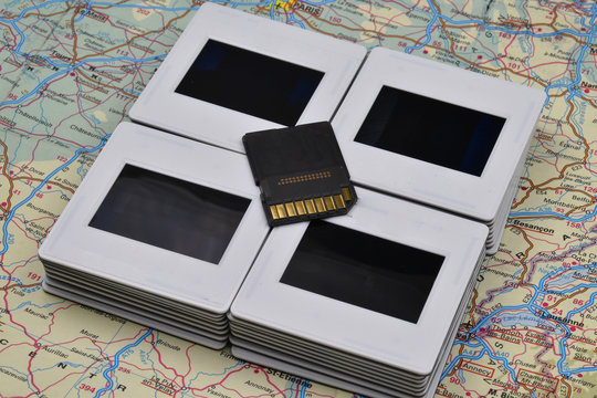 Old and new photography: memory card and vintage amateur slides on a colorful map