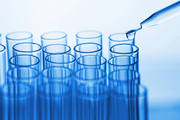 science pipette with a drop of substance over laboratory test tu