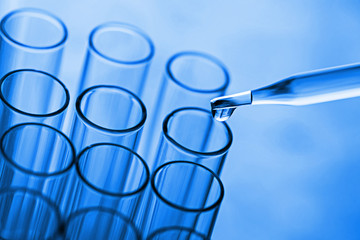 science pipette with a drop of substance over laboratory test tu
