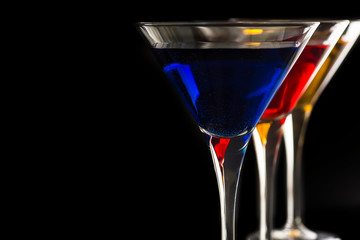 Colorful Cocktails in Martini Glasses on Black Background. Bar Commercials Concept.