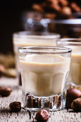 Liquor with nuts in a shot glass on the old wooden background, s