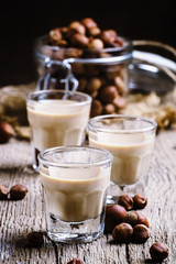 Liquor with nuts in a shot glass on the old wooden background, s