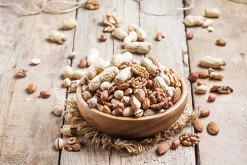 Nuts mix in a bowl on the old wooden background, selective focus