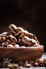 Nuts mix in a bowl on the old wooden background, selective focus