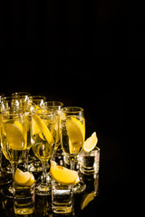 strong alcoholic drinks with lemon in glasses and shotah on a black background