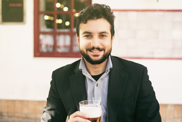 Bearded man drinking beer with suit in outdoors bar terrace